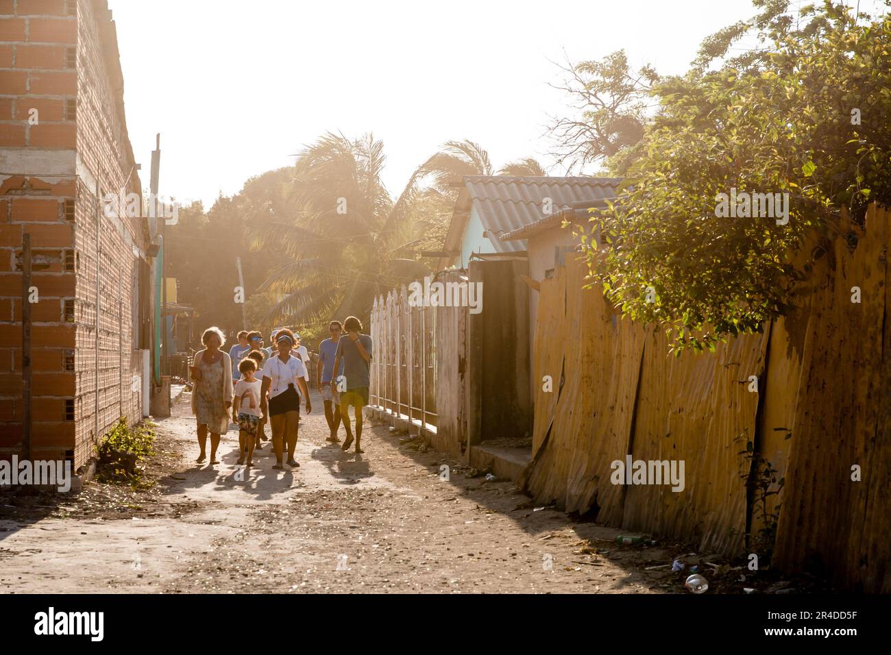 Sunlight streams down on a group of people walking down an alley on Isla Grande Colombia Stock Photo