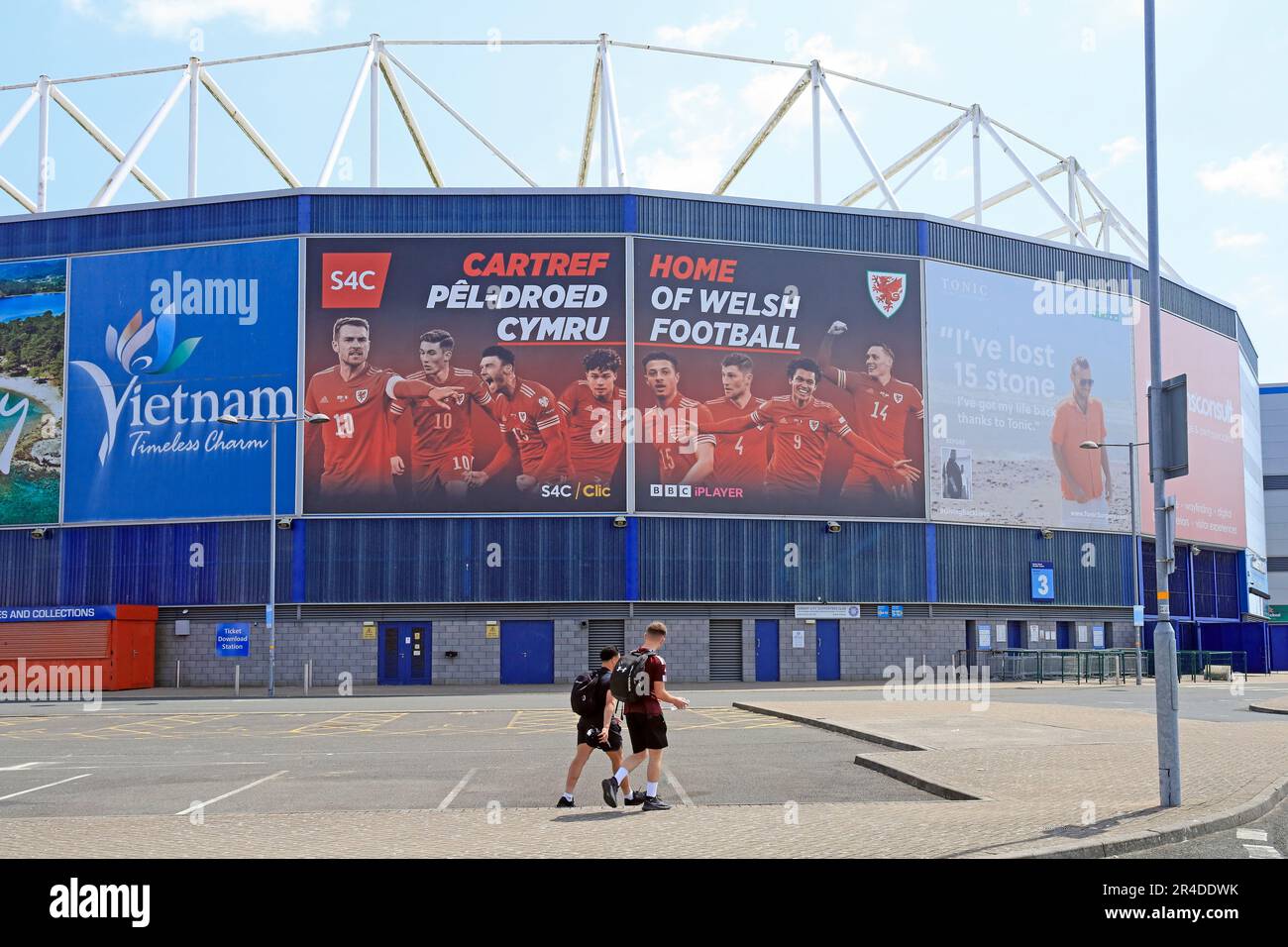 Two young men in sports gear walking past Cardiff City Football Stadium