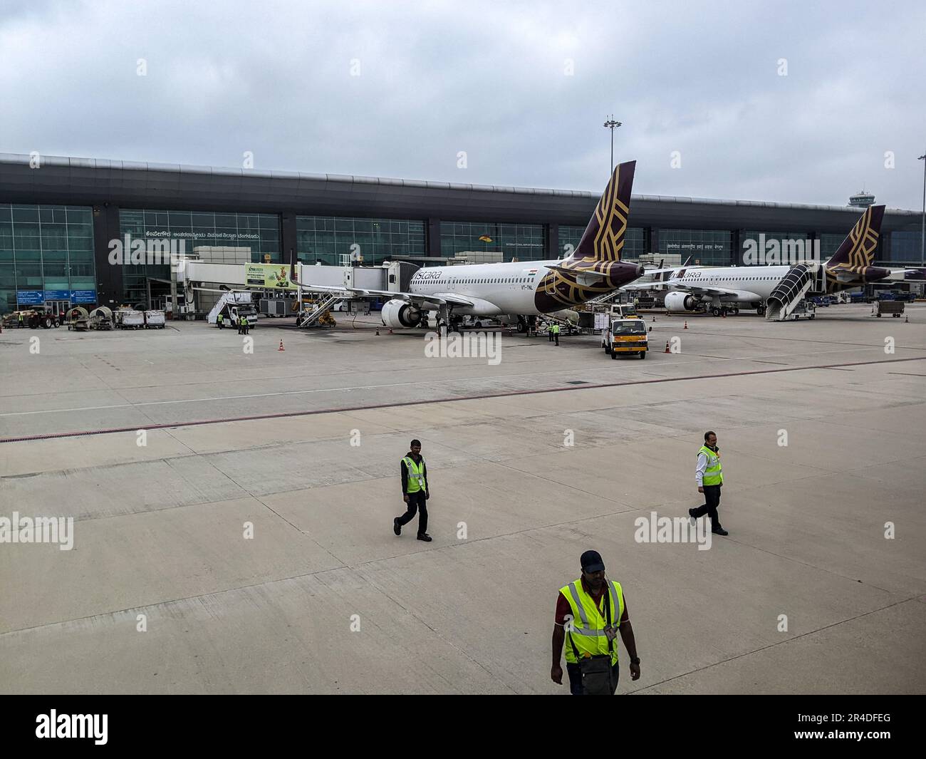 The airport workers on the runway with planes at the terminal in
