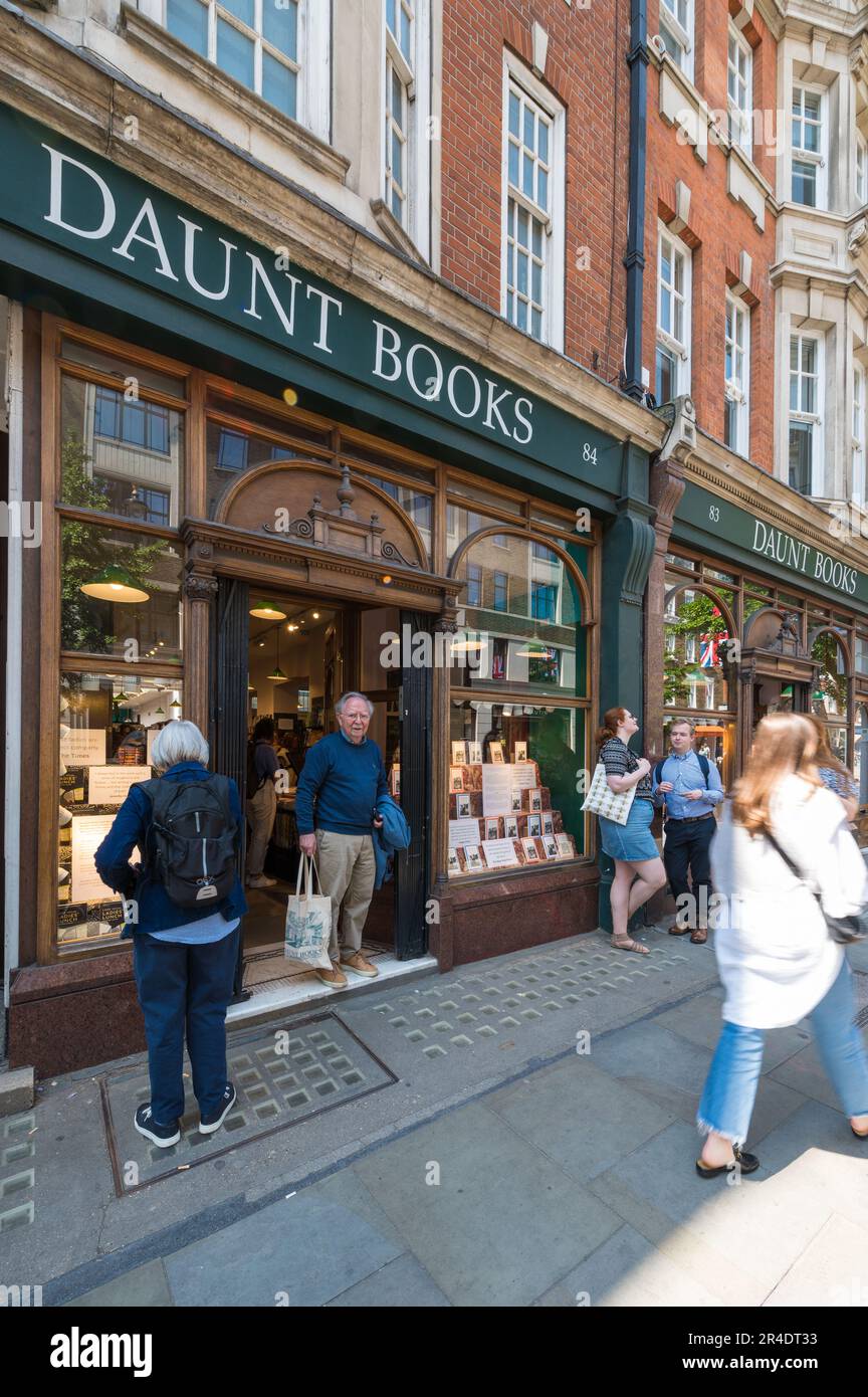 People out and about shopping on a sunny day pass by Daunt Books shop on Marylebone High Street, London, England, UK Stock Photo