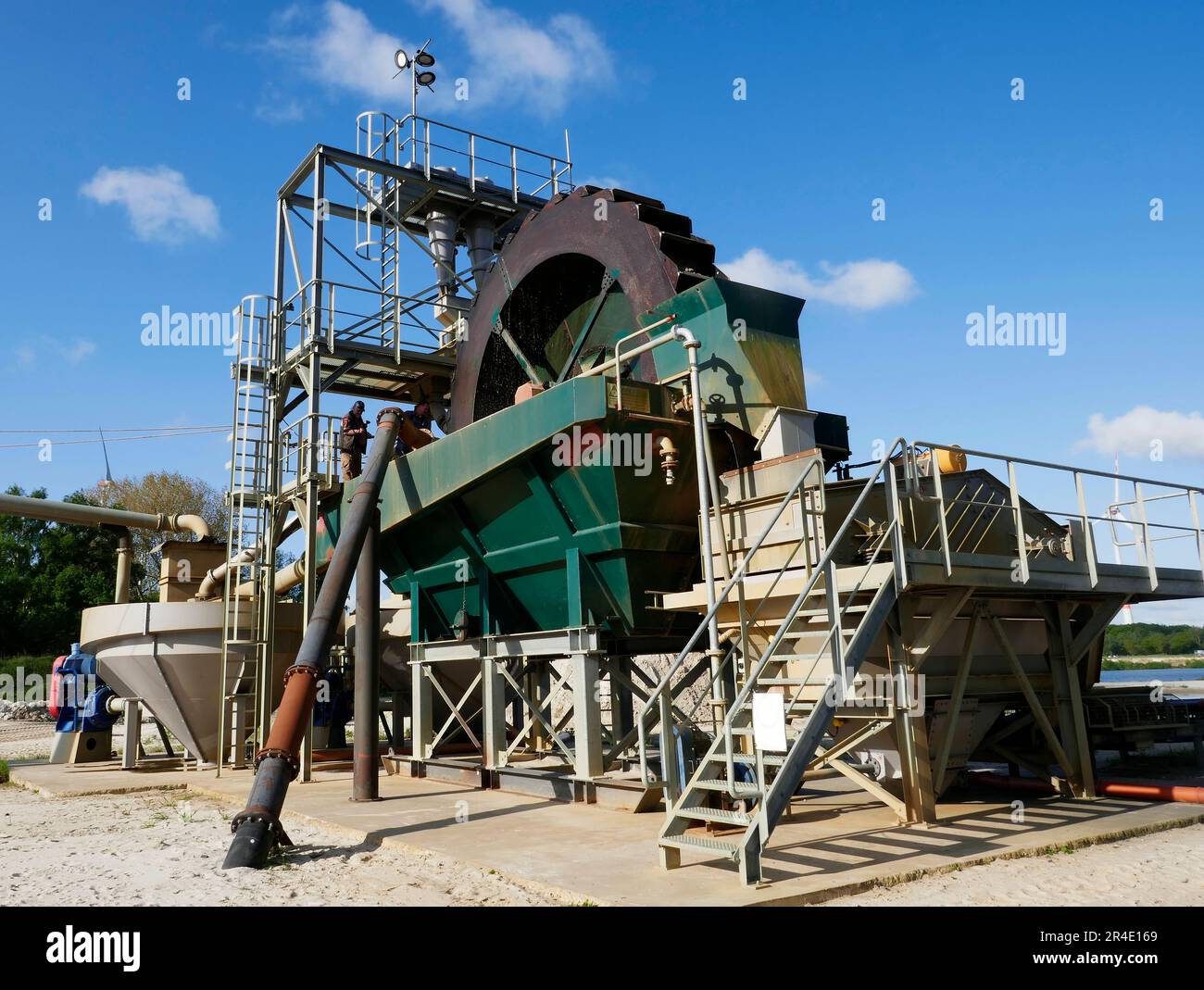 Hoogstede, Germany May 16 2023 Large machine that cleans sand with a bucket wheel. Two people are watching. Only clean coarse sand is needed. Stock Photo