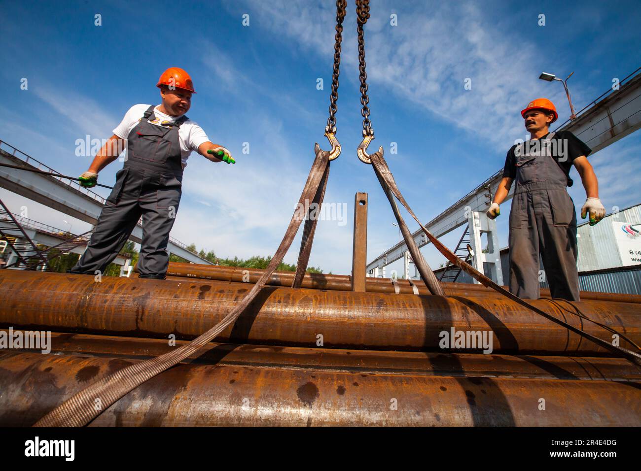 Podolsk, Moscow province - August 02, 2021: Pipes warehouse. Workers installs straps for lifting Stock Photo