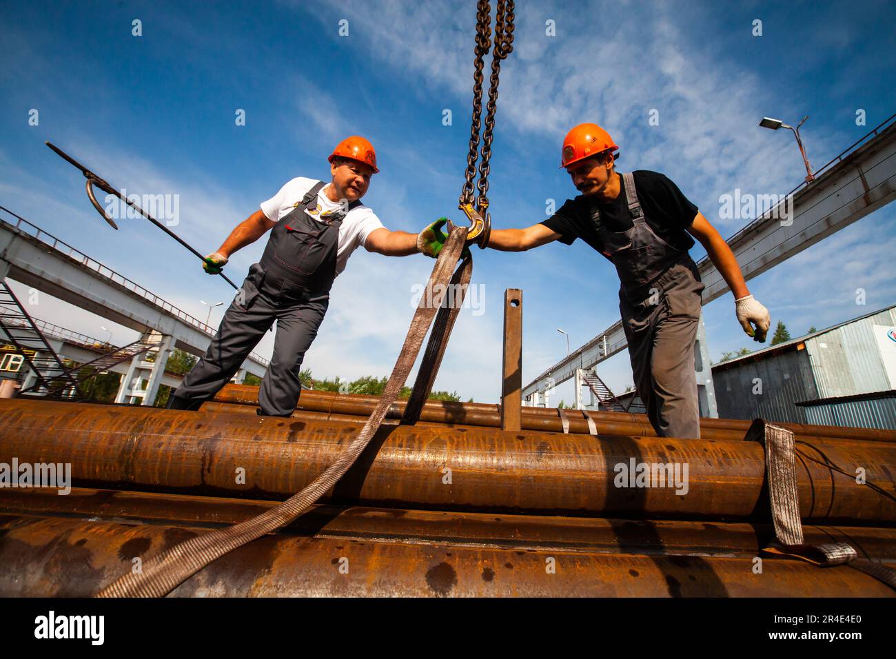 Podolsk, Moscow province - August 02, 2021: Pipes warehouse. Workers installs straps of overhead crane Stock Photo