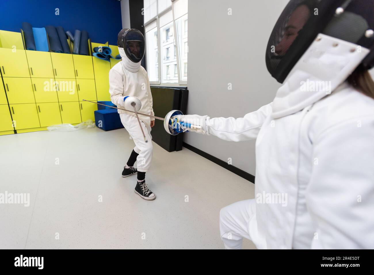 Adults and teens wearing a fencing uniform practicing with foil in the