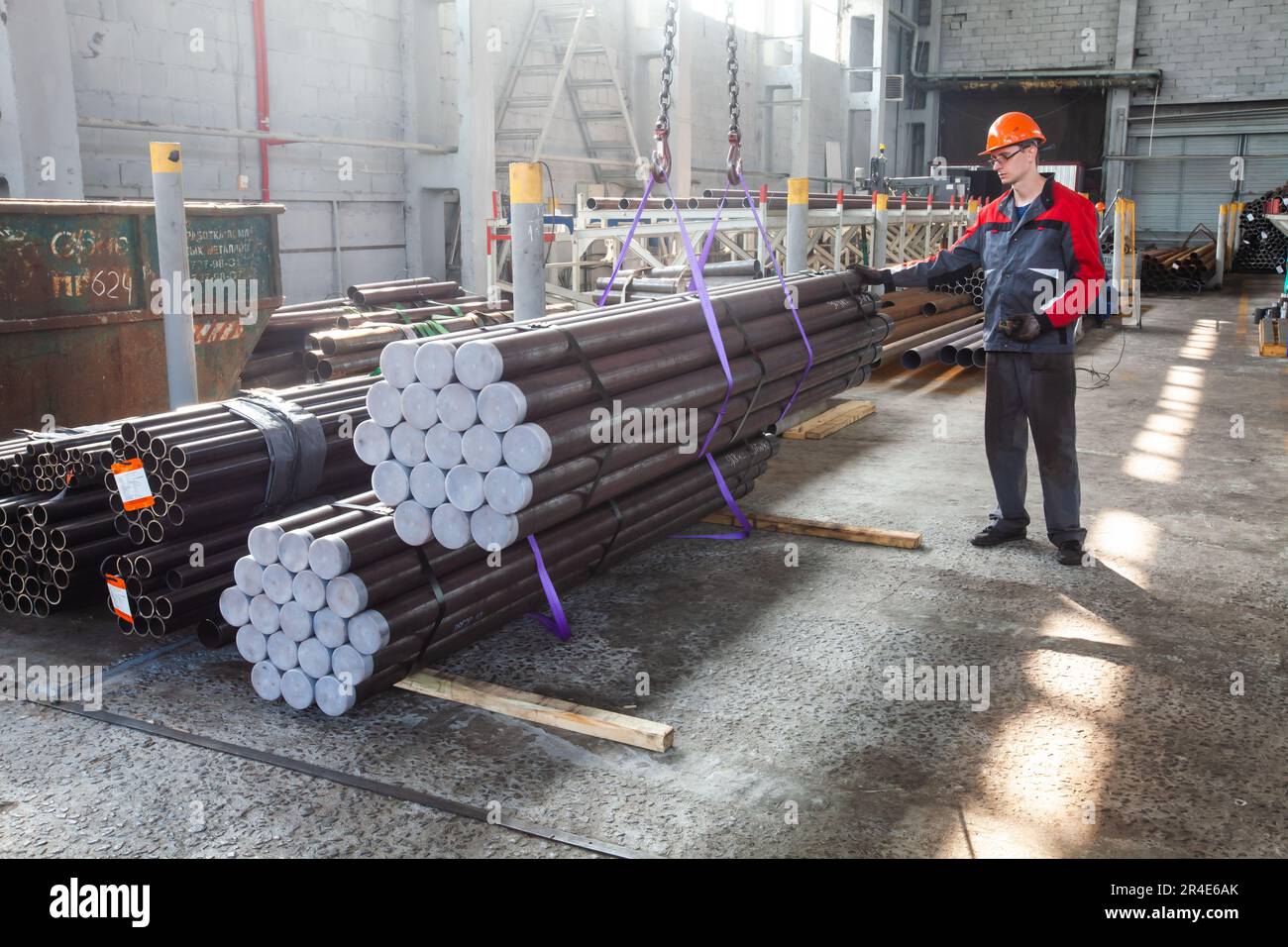 Podolsk, Moscow province - August 02, 2021: Production of oil drill pipes. Young worker lifting ready pipes. Stock Photo