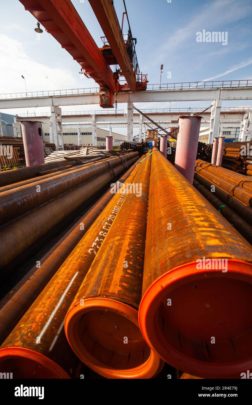 Rusted steel pipes and tubes outdoor warehouse. Overhead crane up. Blue