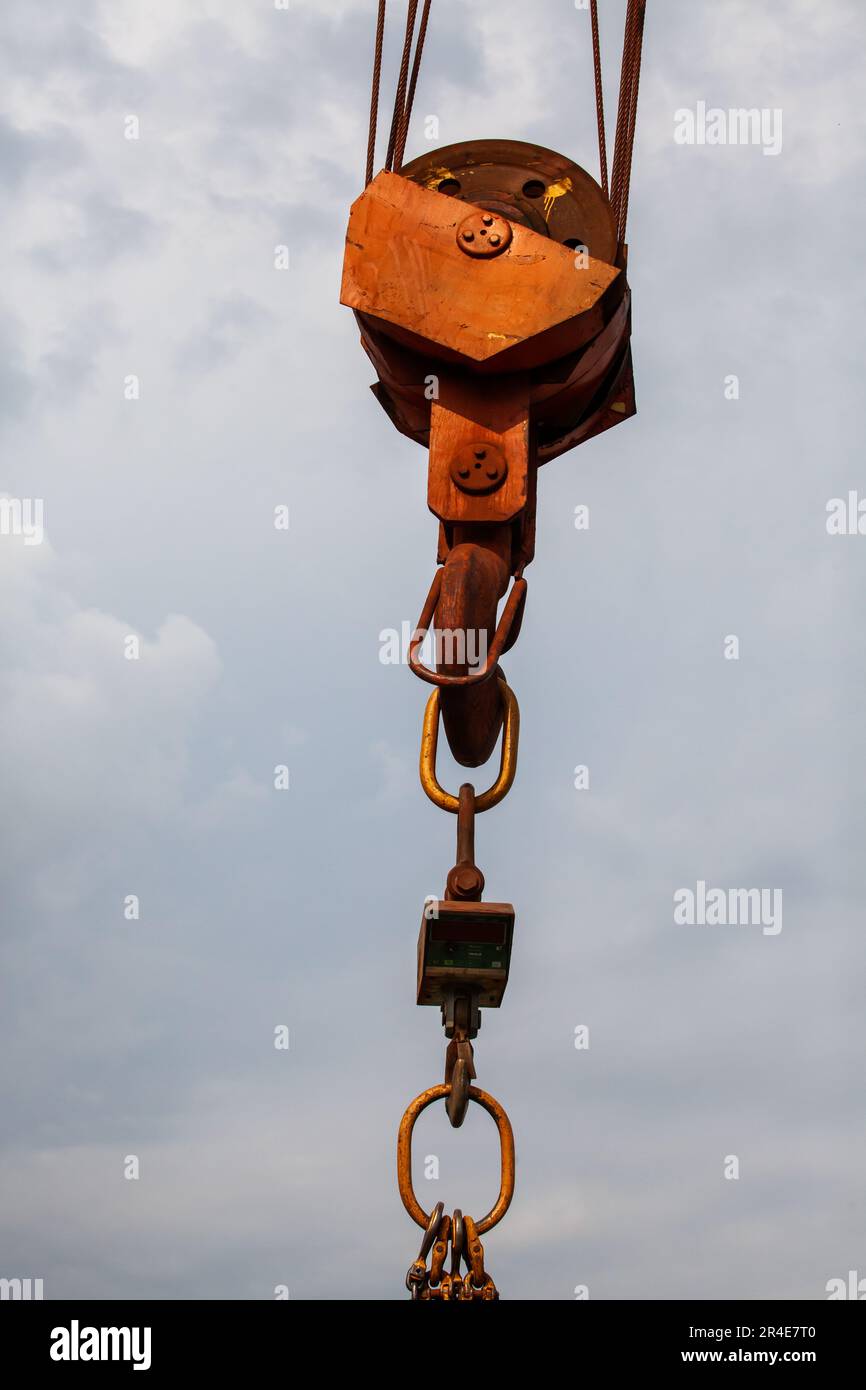 Close-up of rusted crane hook on steel rope against grey sky Stock Photo
