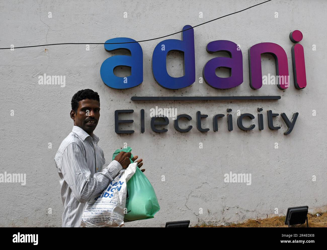 Mumbai, Maharashtra, India. 27th May, 2023. A man walks past the Adani electricity logo on the