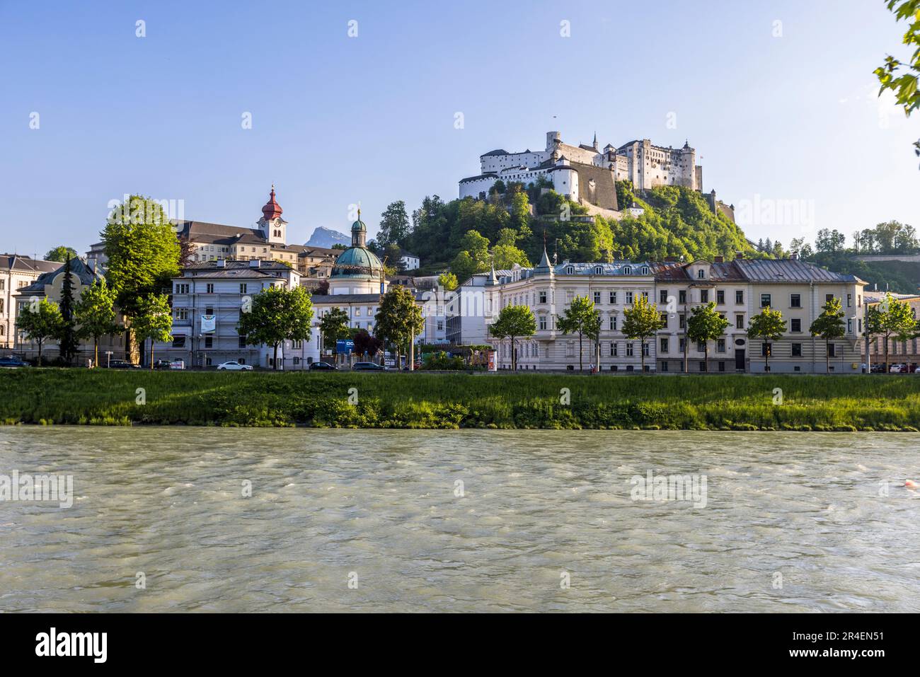 The banks of the Salzach River with views of the Hohensalzburg fortress and cathedral quatier is a popular picnic spot for couples in Salzburg, Austria Stock Photo