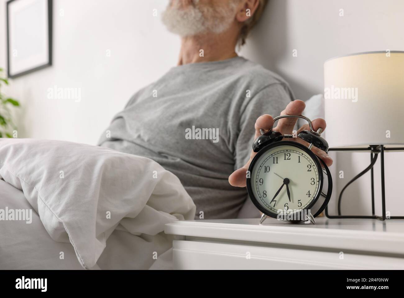 Man turning off alarm clock in bedroom, closeup Stock Photo Alamy