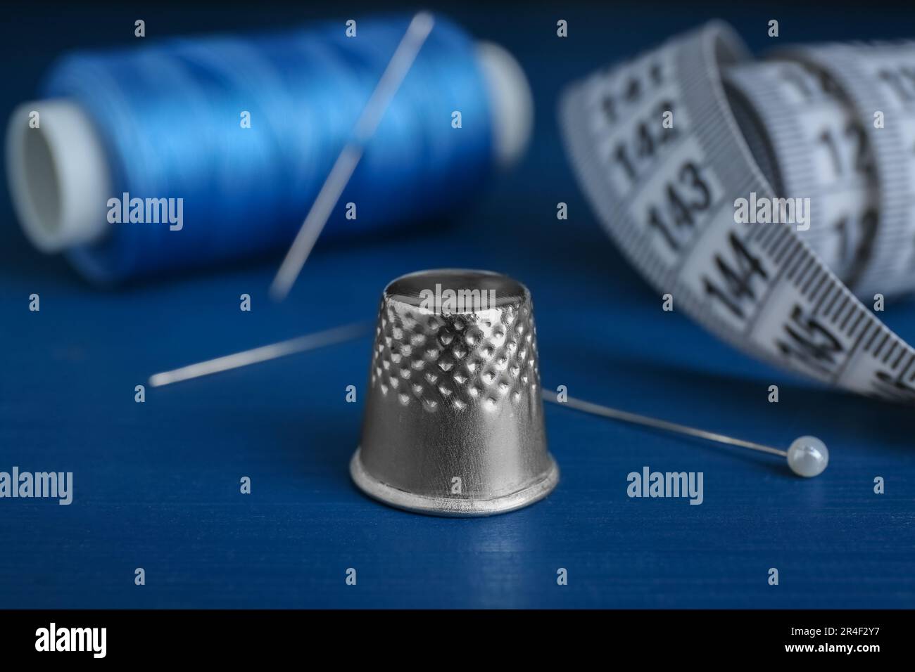 Silver thimble on blue wooden table. Sewing accessories Stock Photo