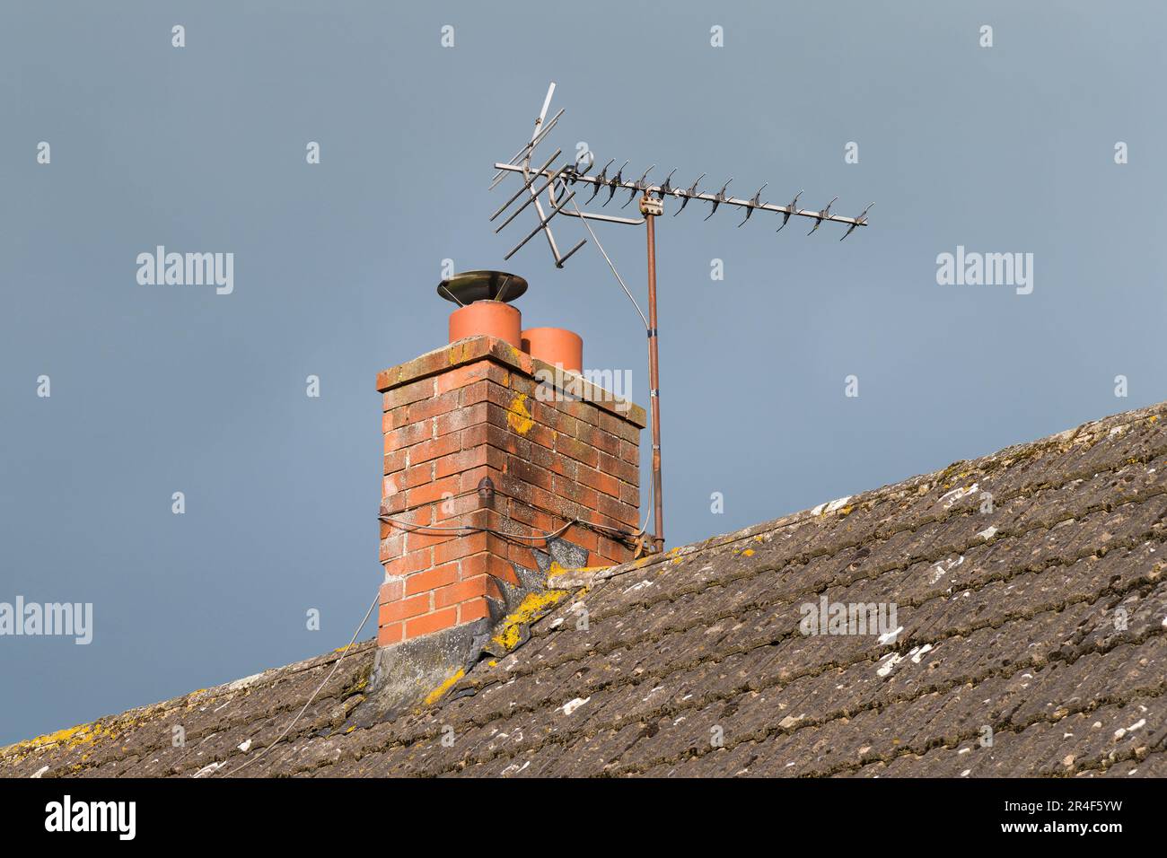 Television antenna on brick chimney above tiled roof to receive TV