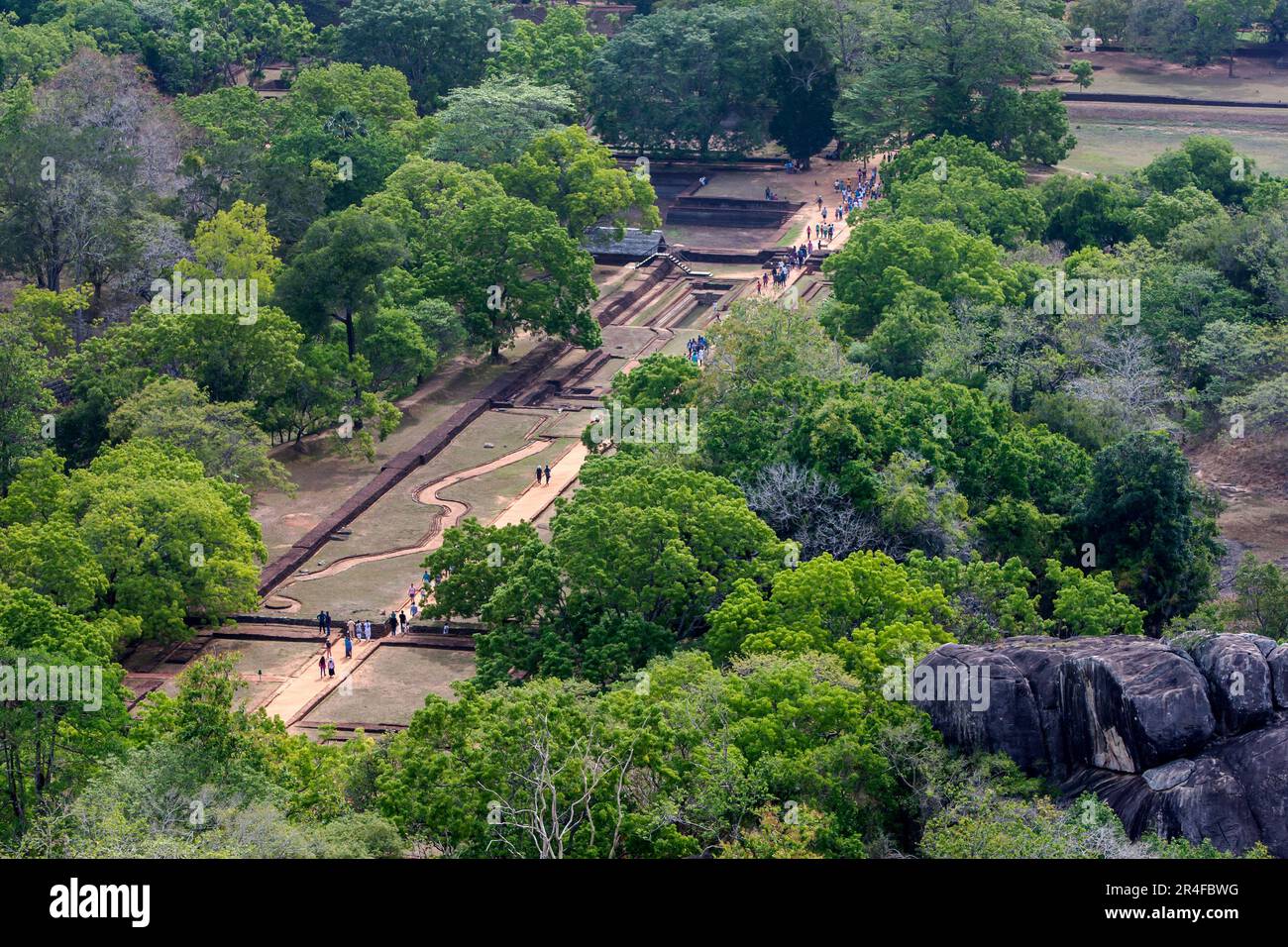 Visitors to Sigiriya Rock Fortress in central Sri Lanka walk through the ruins of the Royal Gardens. Stock Photo