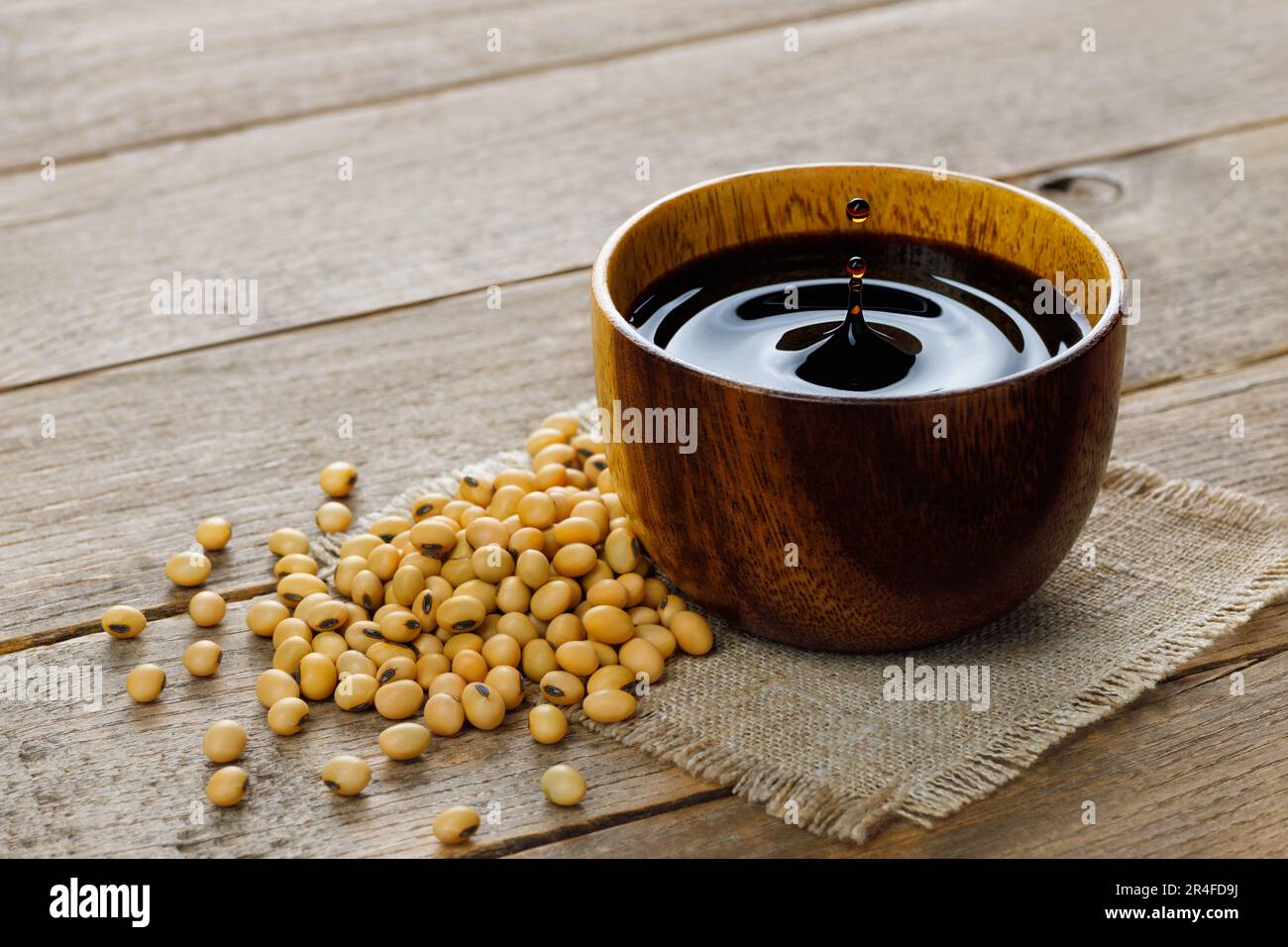 soy sauce in bowl with falling drops and splash on table Stock Photo