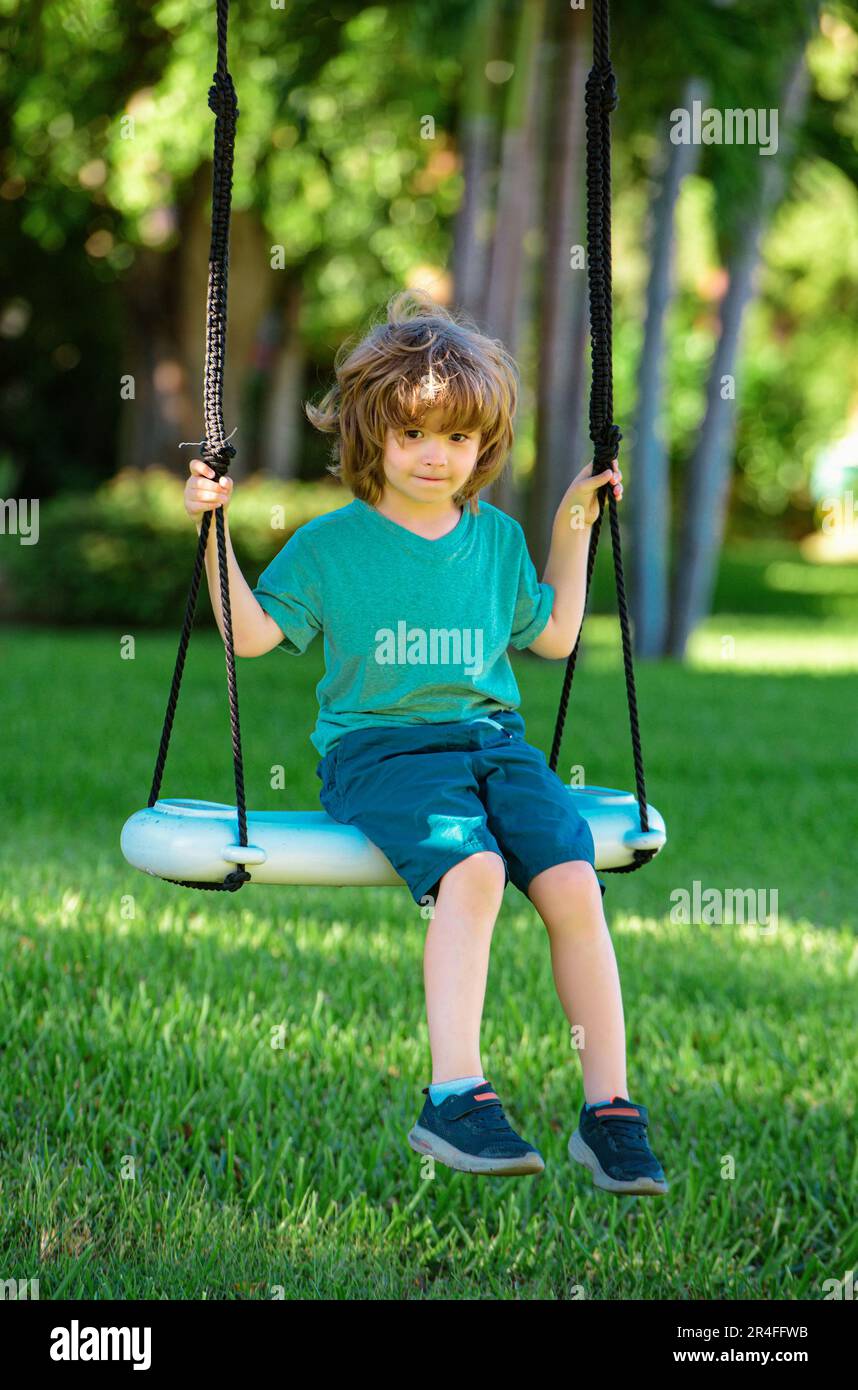 Child playing outdoor. Kids swing on backyard. Happy cute little boy
