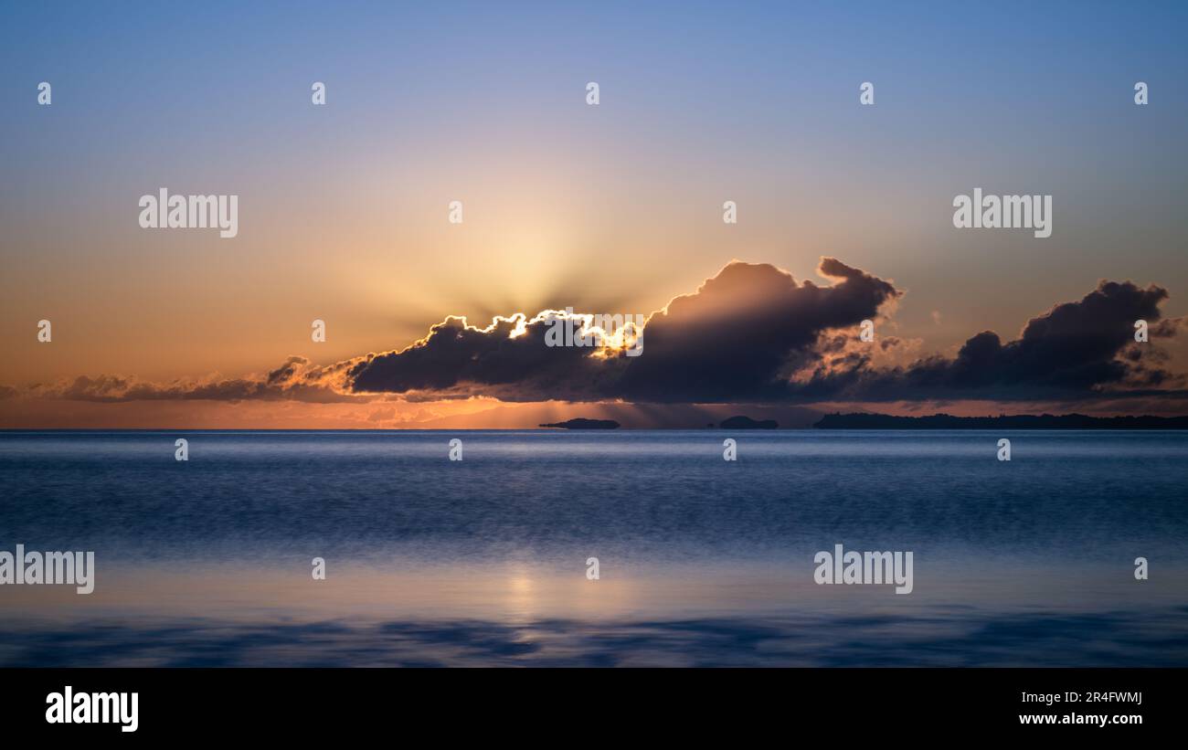 Sunbeams shining through clouds at sunrise. Auckland. Stock Photo