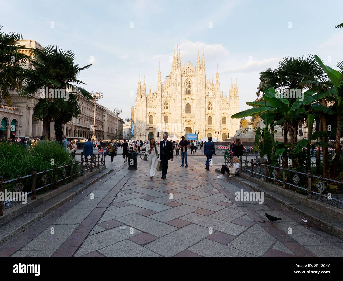 Couple walk amongst the crowds with the Duomo behind lit by the evening light, City of Milan, Lombardy, Italy Stock Photo