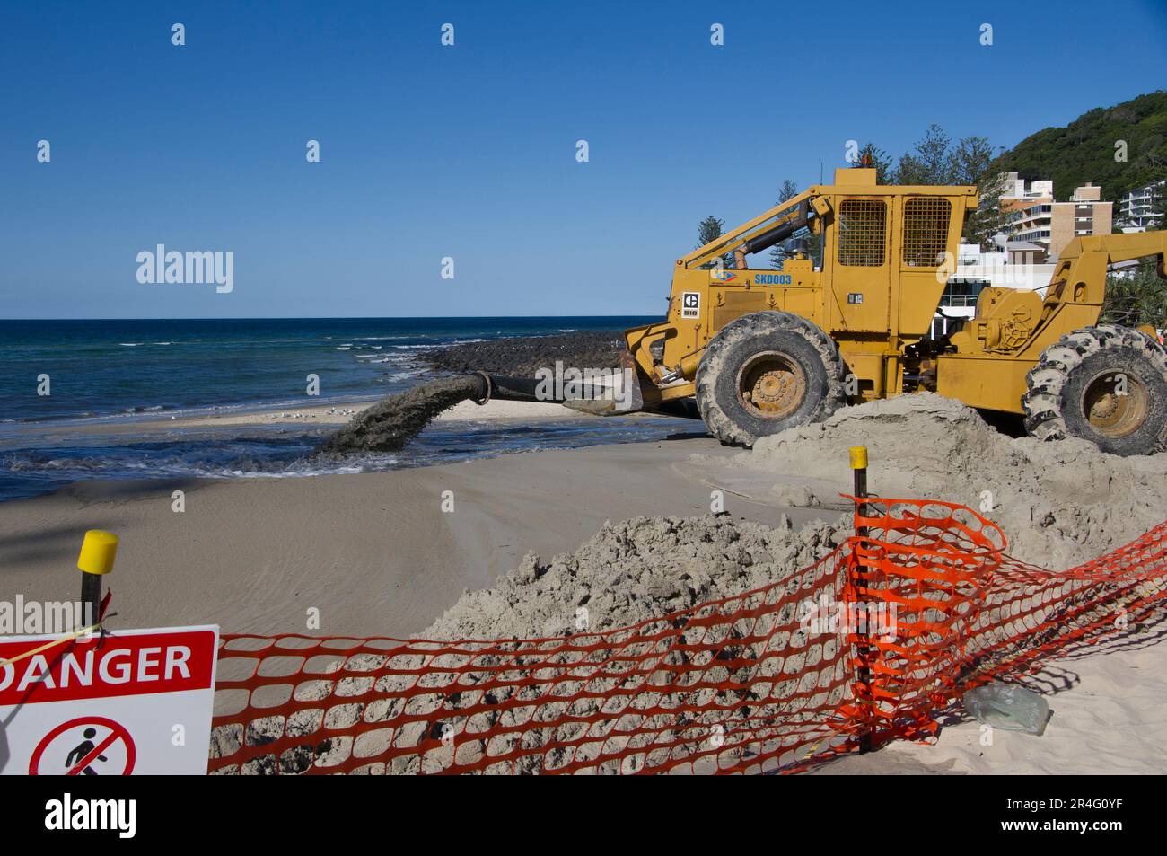 Sand pumping on Burleigh beach on Gold Coast, Australia. Annual beach repair and sand replemishment. Yellow pump vehicle. Beach fenced off for work. Stock Photo