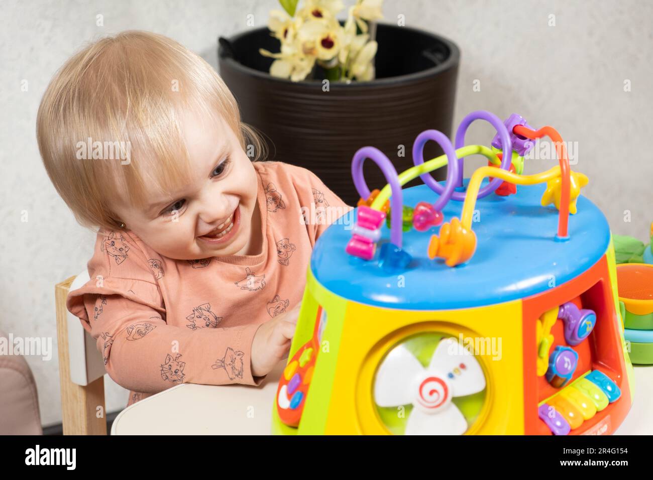 A one-and-a-half-year-old girl plays with a musical glowing toy ...