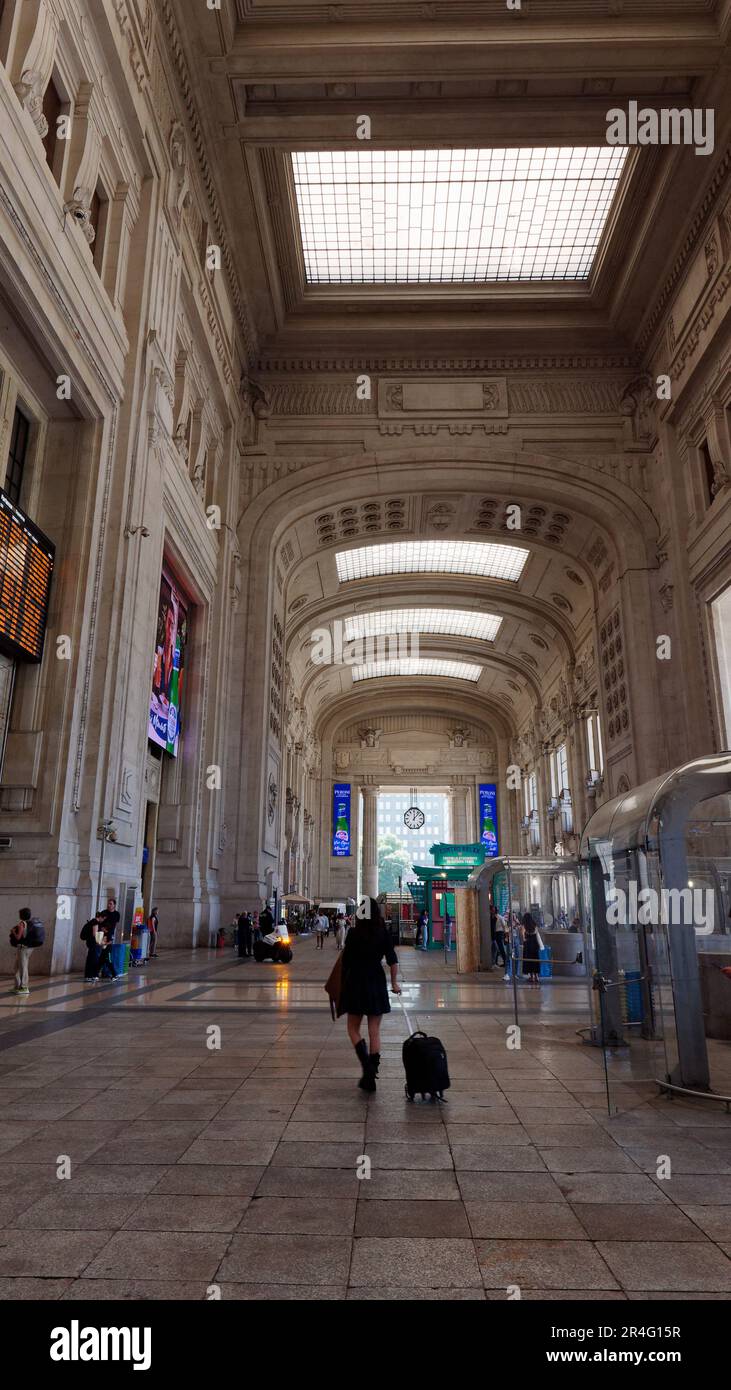 Interior of Milan Centrale Railway Station. Travellers wheel their suitcases inside the station Stock Photo
