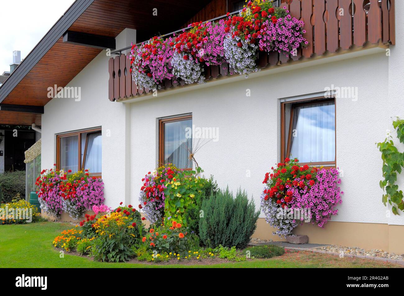 Baden-Wuerttemberg, Black Forest house with flower garden in summer, different summer flowers in the garden, balcony with petunias and geraniums Stock Photo