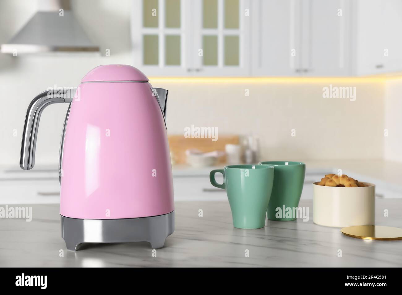https://c8.alamy.com/comp/2R4G581/modern-electric-kettle-cups-and-cookies-on-table-in-kitchen-2R4G581.jpg