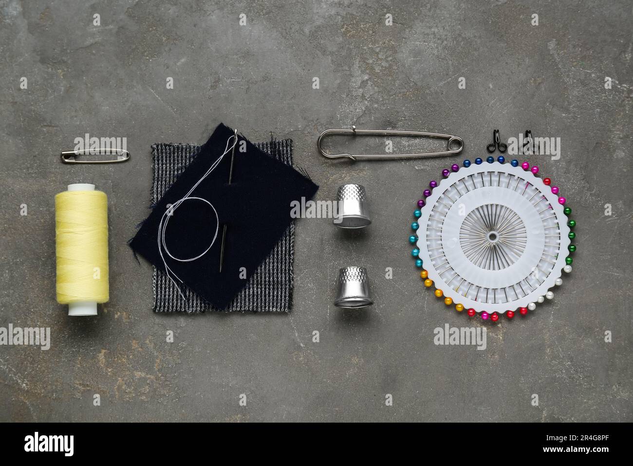 Flat lay composition with thimbles and different sewing tools on grey table Stock Photo