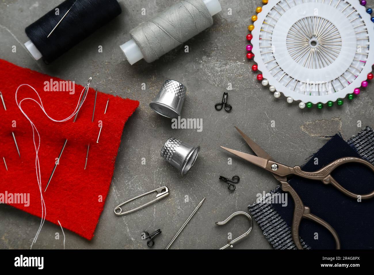 Flat lay composition with thimbles and different sewing tools on grey table Stock Photo
