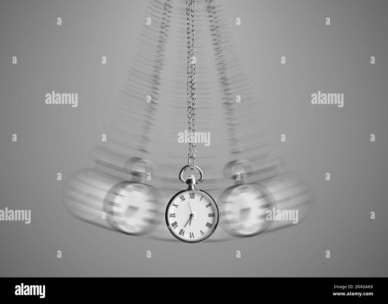Hypnosis session. Vintage pocket watch with chain swinging on grey