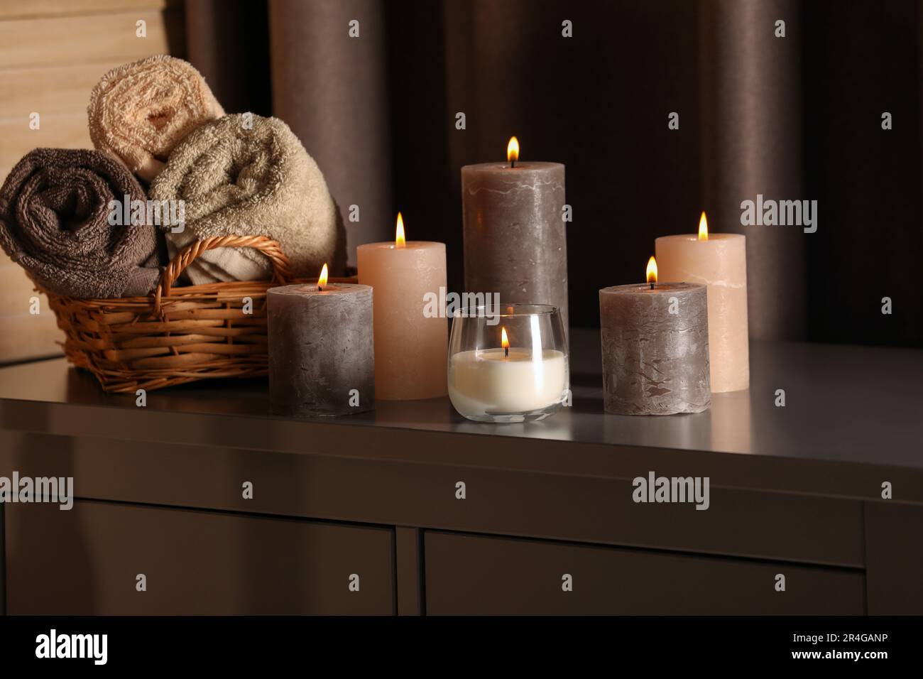 Spa composition with burning candles and rolled towels on cabinet in ...