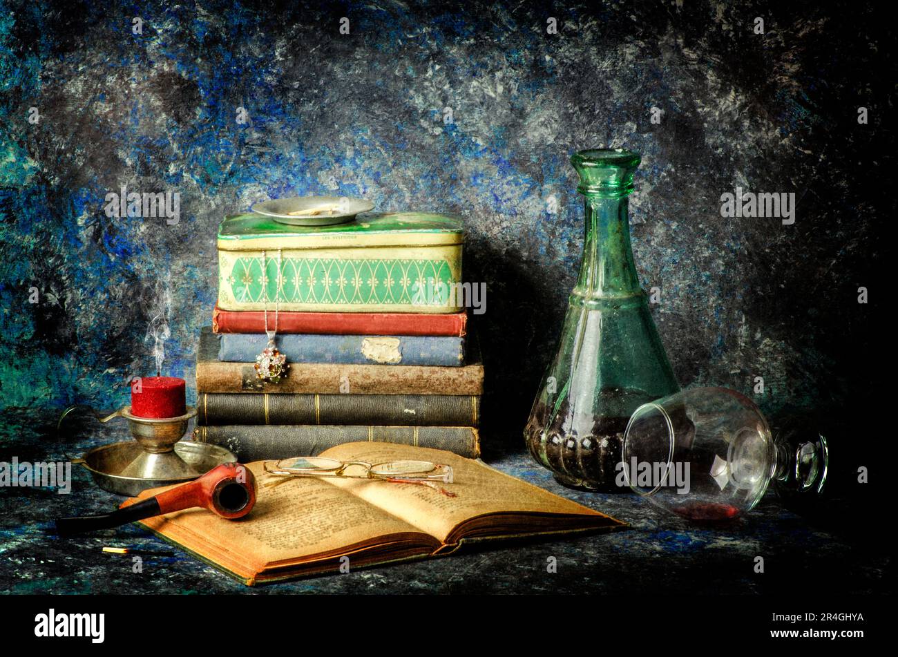 Classic still life with old books, antique glass bottle full of drink ,pipe, candle, old box, glasses placed together on vintage background.. Stock Photo
