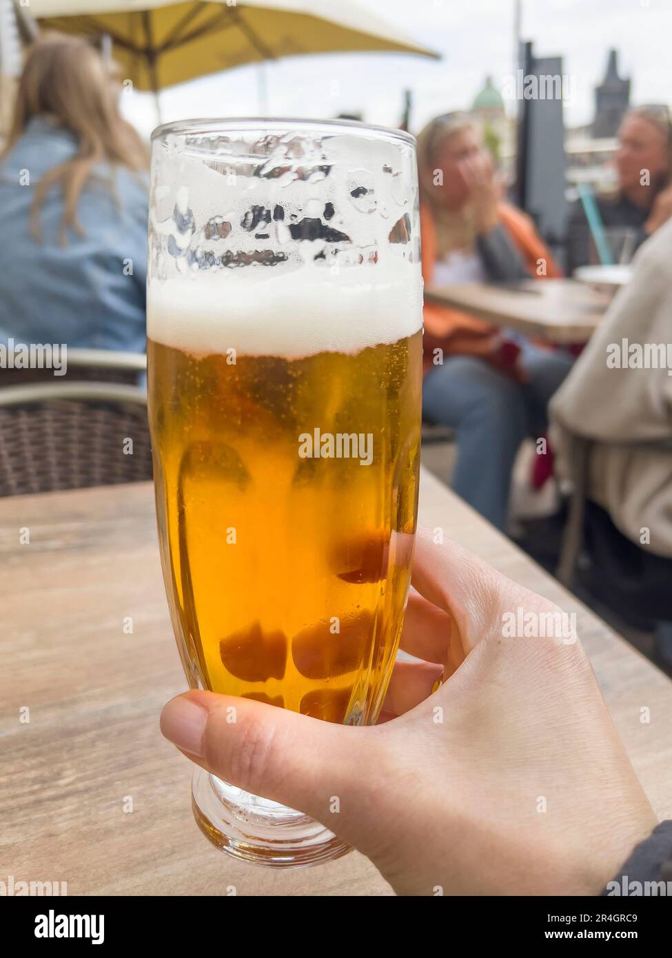 beer, female hand holding glass of cold beer with selective focus over blurred people in a cafe or restaurant. alcohol drink concept photo Stock Photo