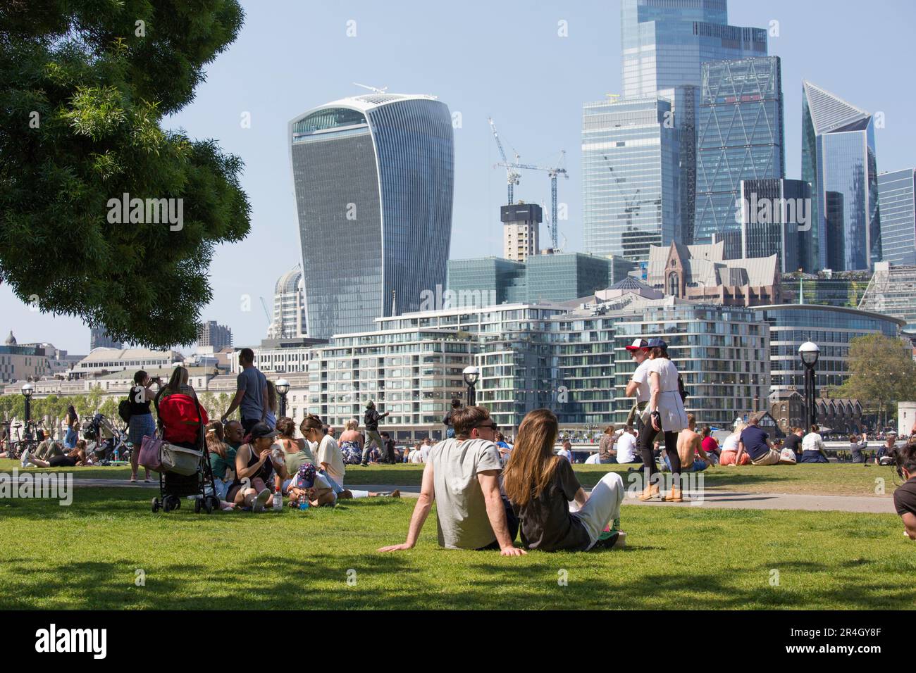 Couple sunbathing and tourists in front of the city of London Sky