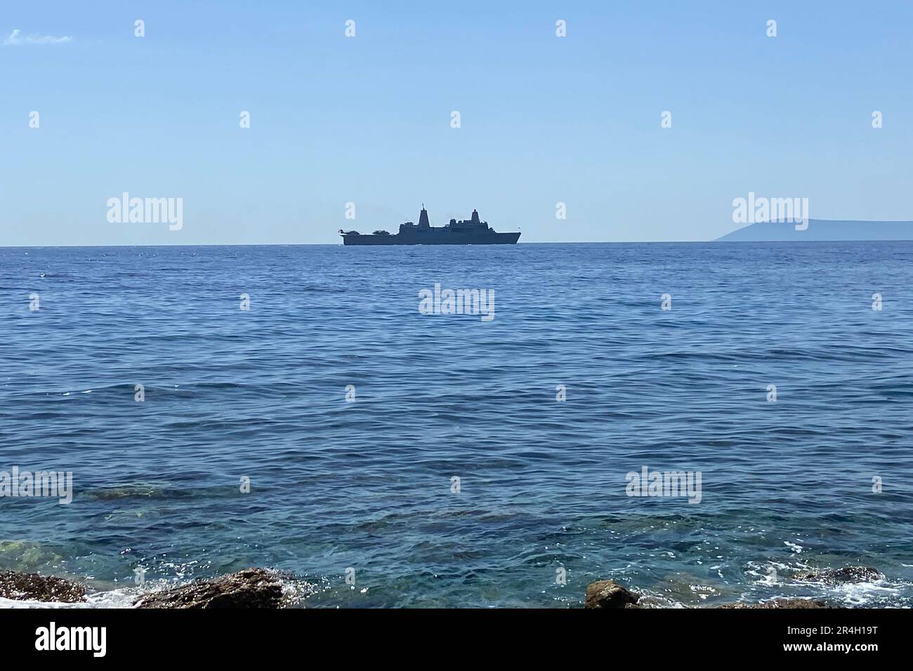 Navy activity on the Aegean Mediterranean Sea. Military vehicles ships transport for military drill operation in open sea with rocks on the seashore. Stock Photo