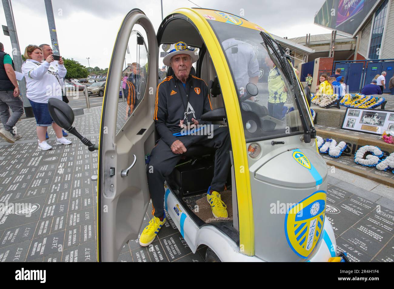A Leeds United supporter arrives in his branded mini car sits next to the Billy Bremner statue