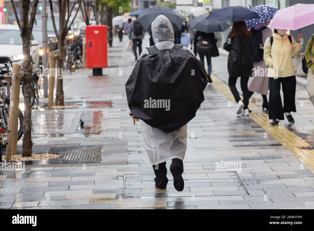 picture of a erson wearing rainproof clothing who walks on a pedestrian walkway in the city Stock Photo