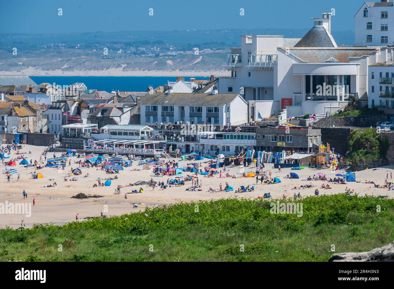 St Ives, UK. 27th May, 2023. People flock to the beach, in front of the Tate St Ives, to sunbathe as well as take part in watersports and boat trips - Sunny weather for the bank holiday Credit: Guy Bell/Alamy Live News Stock Photo