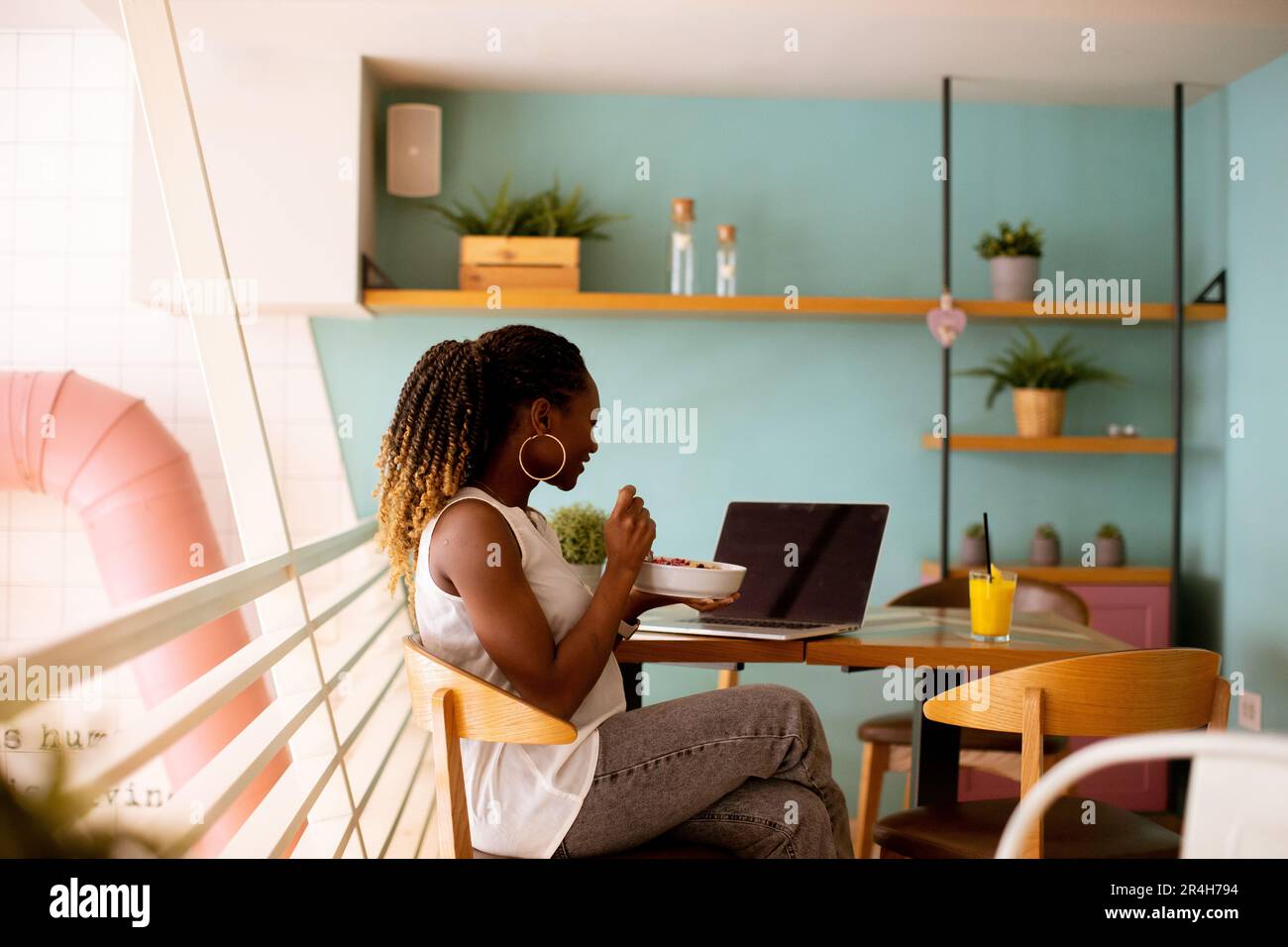 Pretty young black woman having a healthy breakfast while working on ...