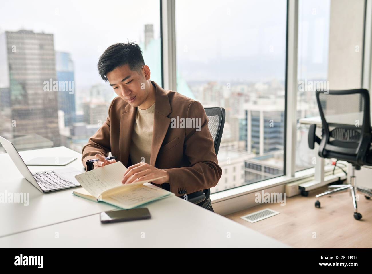 Busy young Asian business man working in office checking notebook. Stock Photo