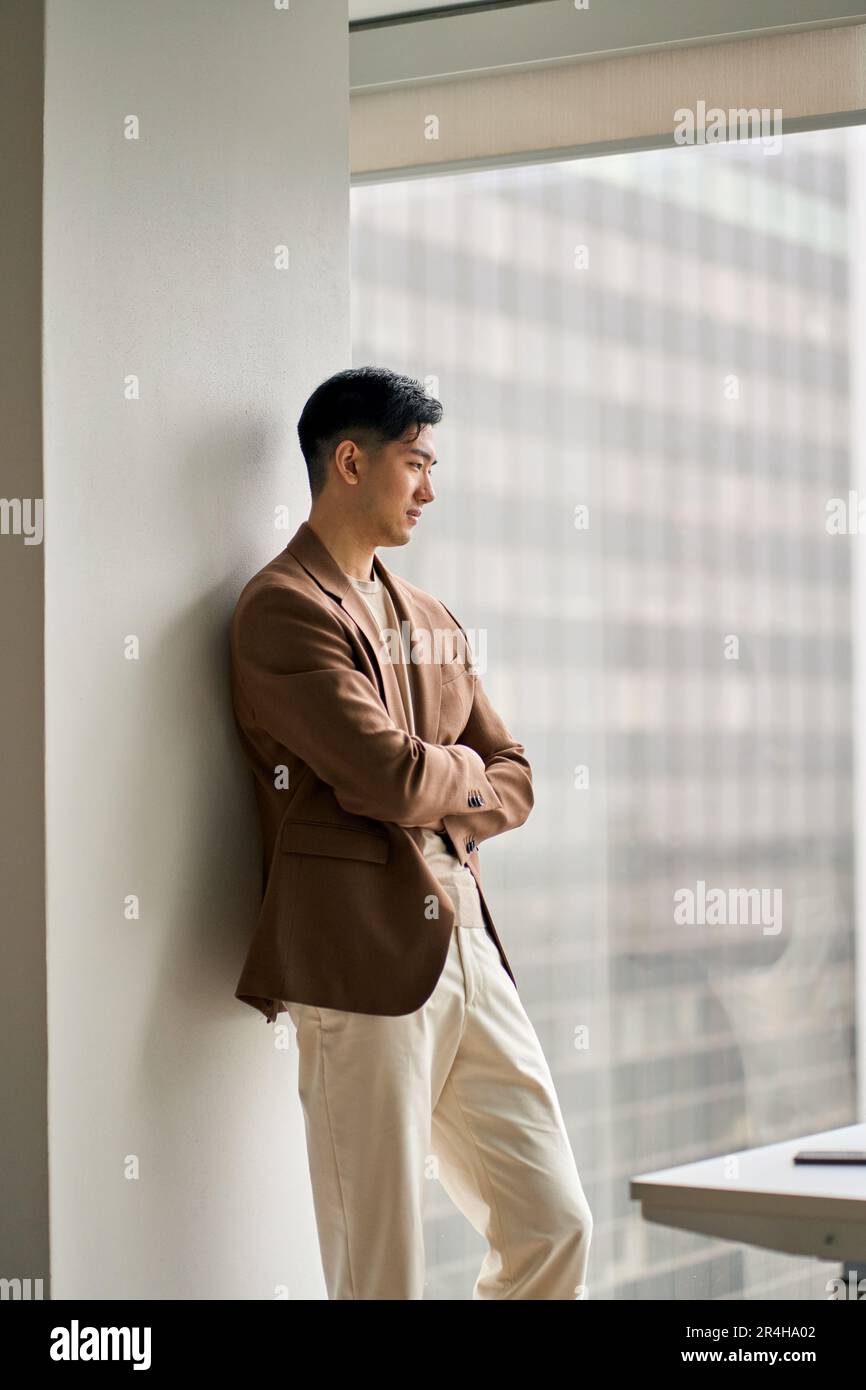 Young confident Asian business man executive looking at window thinking. Stock Photo
