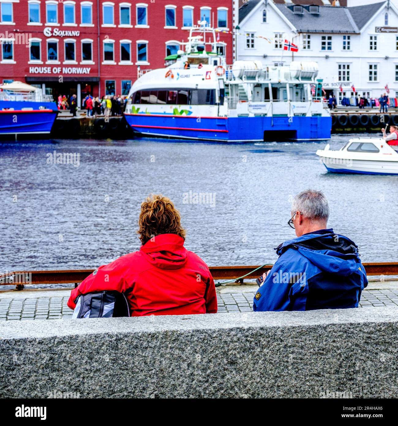 Stavanger, Rogaland, Norway, May 19 2023, Middle Age Couple Sitting Relaxing Waterside Stavanger Harbour With Traditional Old dock Side buildings And Stock Photo