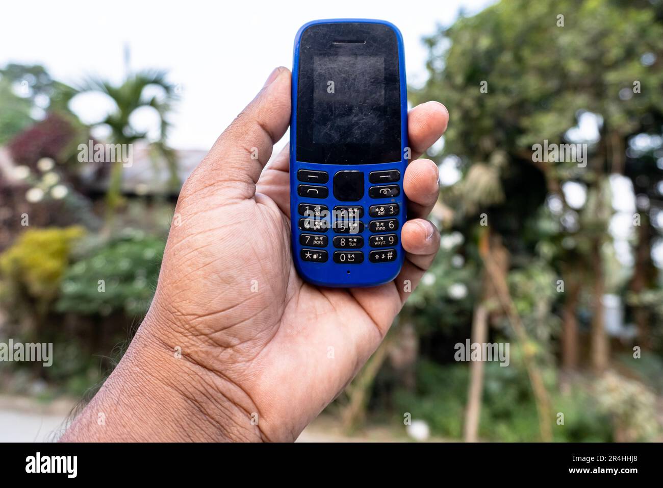A button phone on hand isolated on a natural background Stock Photo