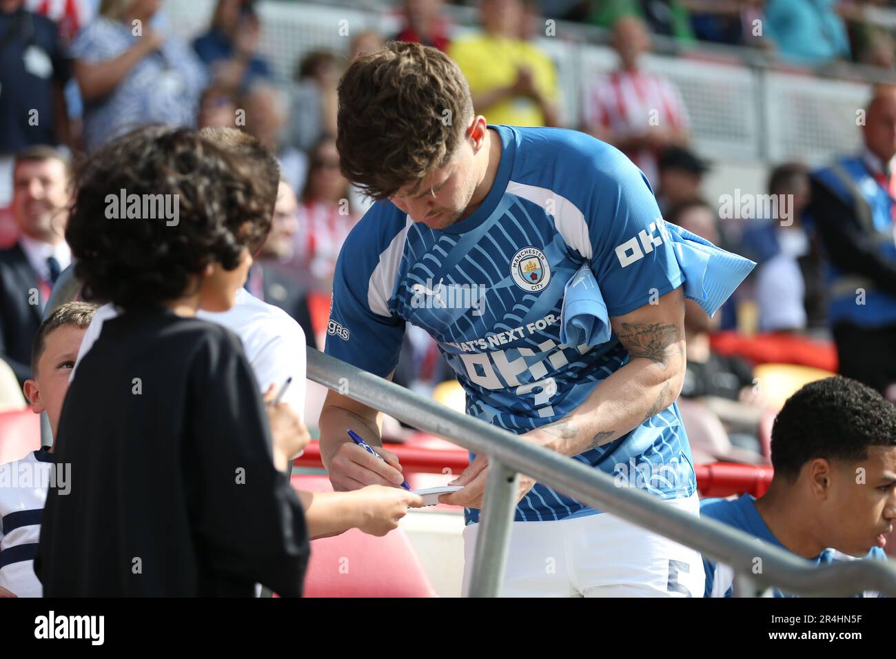 London, UK. 28th May, 2023. John Stones of Manchester City signs autographs from the bench during the Premier League match between Brentford and Manchester City at Gtech Community Stadium, London, England on 28 May 2023. Photo by Pedro Soares. Editorial use only, license required for commercial use. No use in betting, games or a single club/league/player publications. Credit: UK Sports Pics Ltd/Alamy Live News Stock Photo