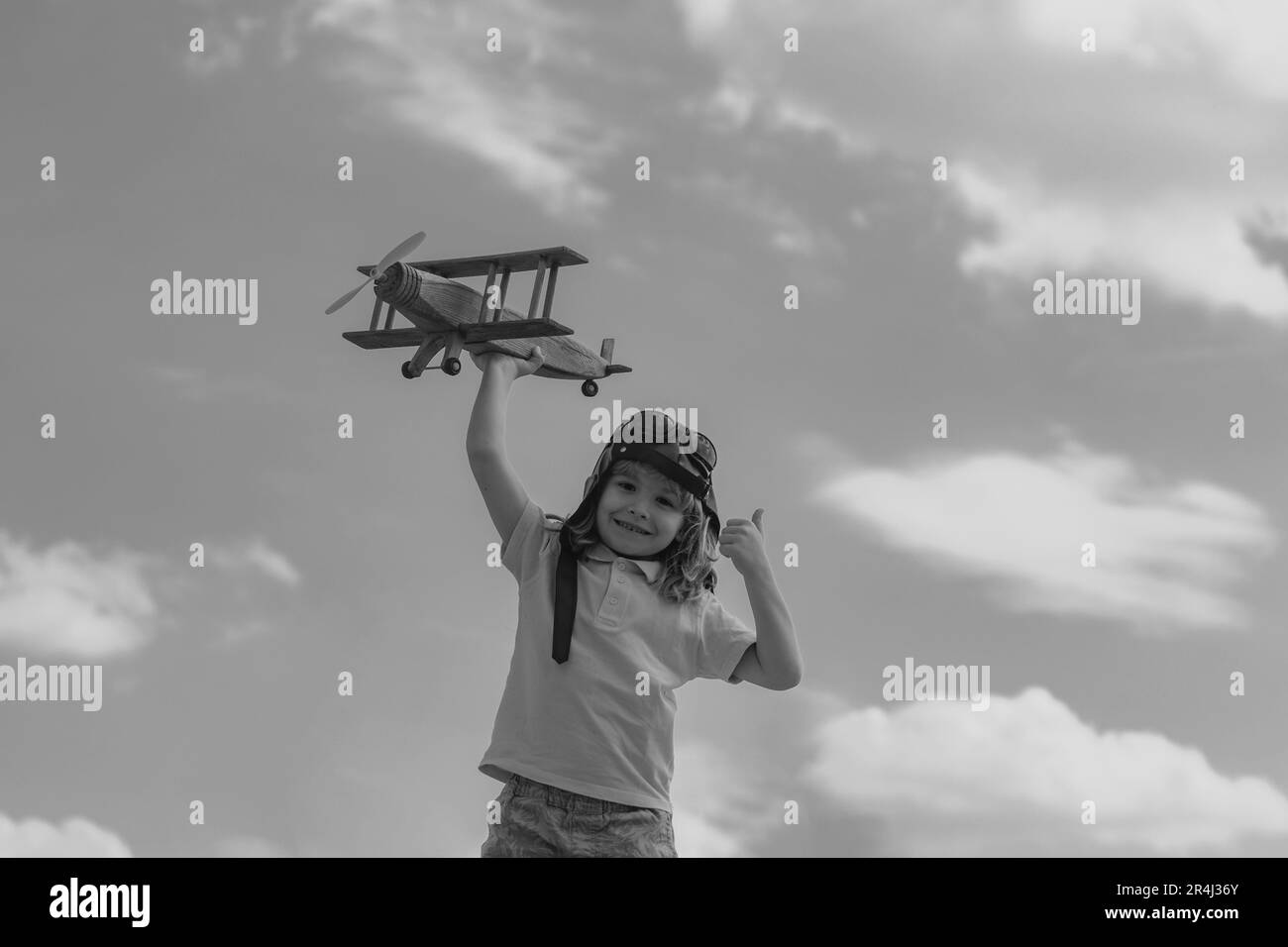 Child boy with pilot goggles and helmet playing with wooden toy