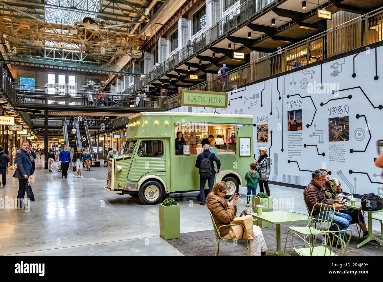 People drinking coffee at a Maison Ladurée branded catering van on the ground floor of Turbine Hall A at Battersea Power Station, London ,SW11 Stock Photo