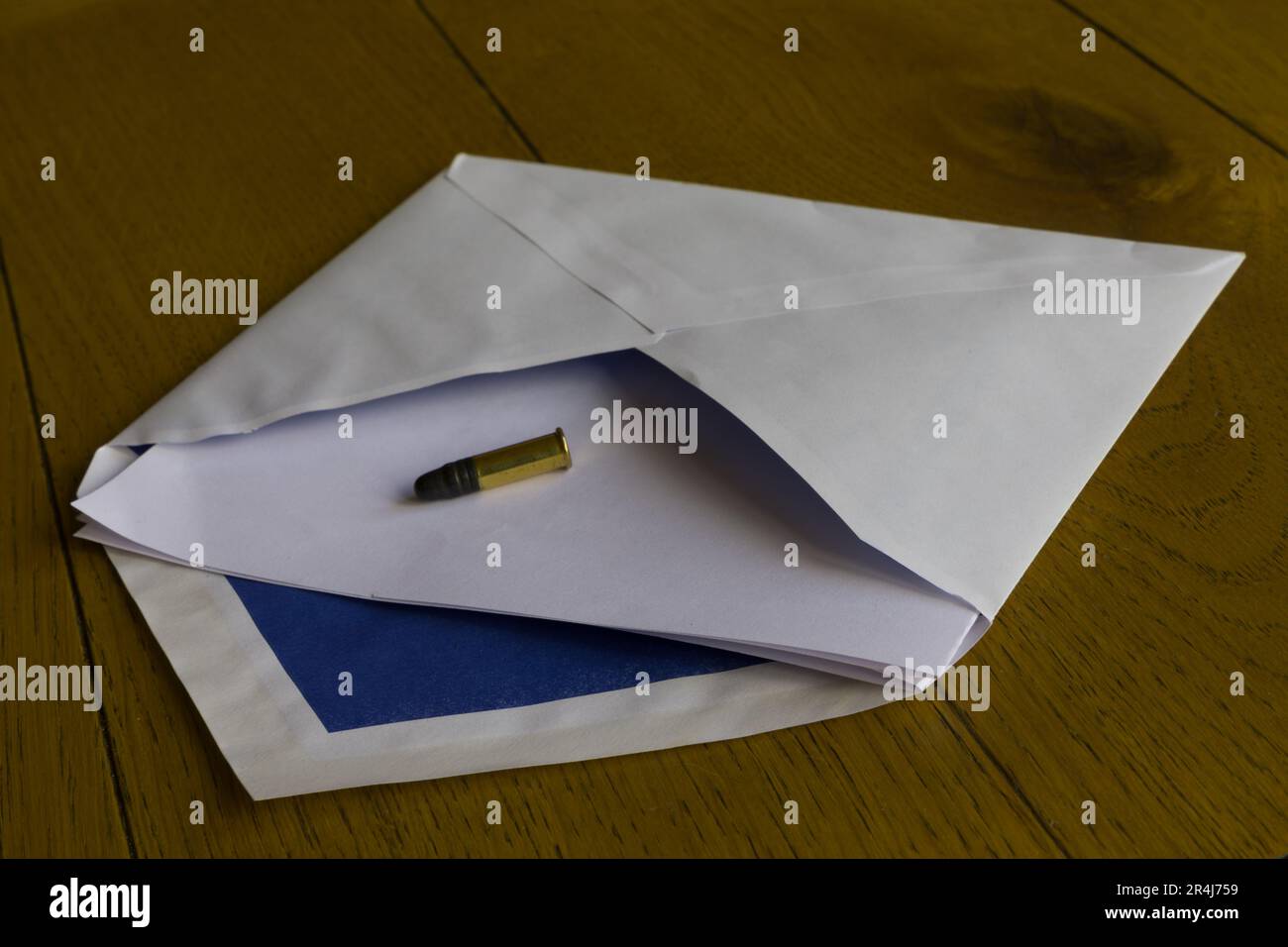 An envelope with a bullet letter. Concept for extortion and threatening someone. Stock Photo