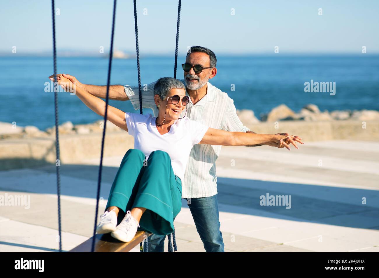 Cheerful Mature Couple Swinging At Sea Enjoying Summer Day Outdoors Stock  Photo - Alamy