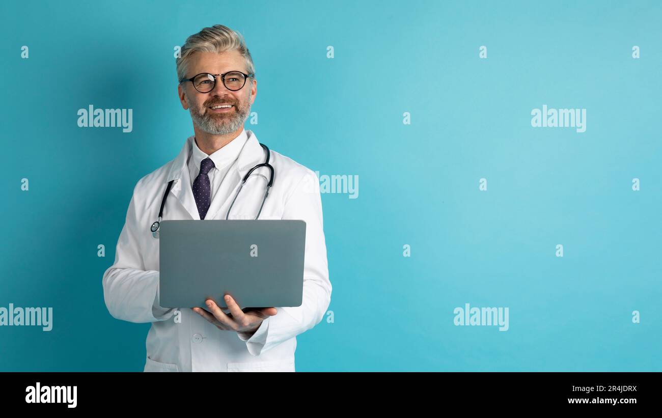 Friendly middle aged doctor using laptop, copy space Stock Photo