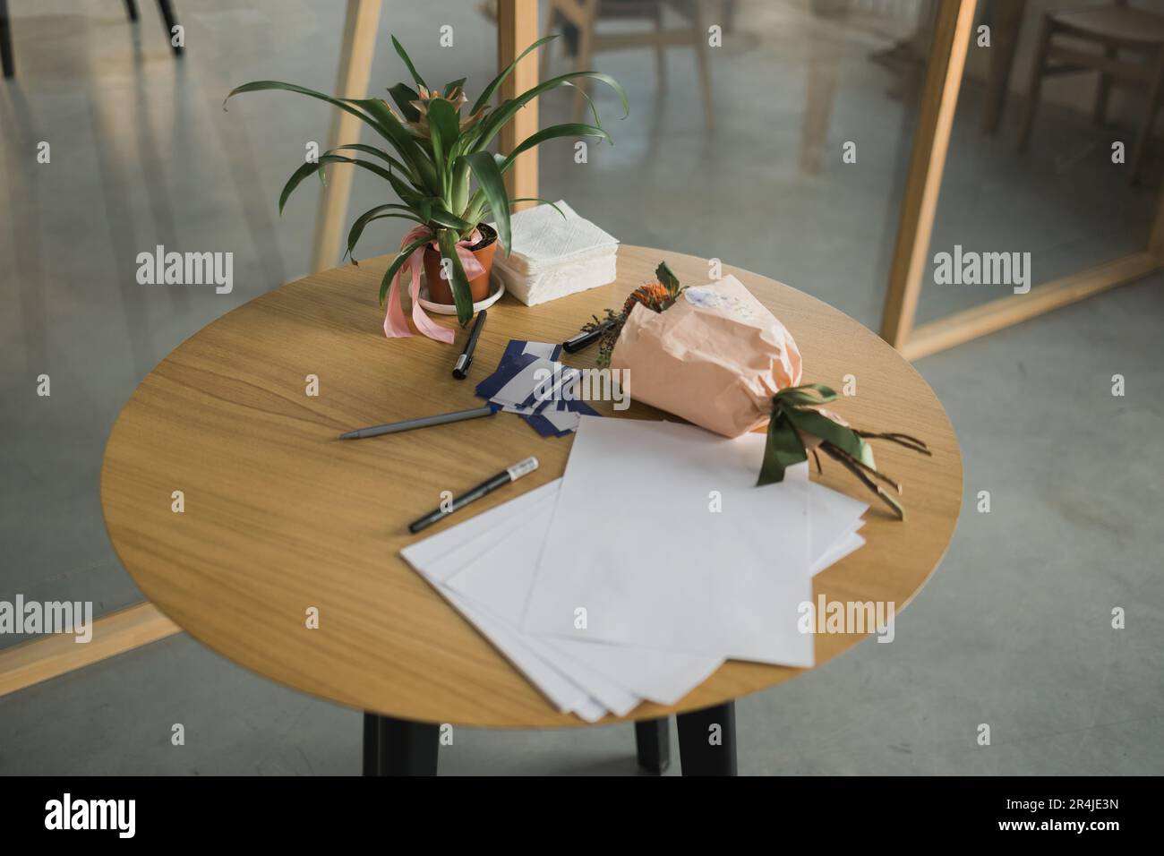 Table with business papers decorated with houseplants guzmania on desk. Exotic potted houseplants. Stock Photo