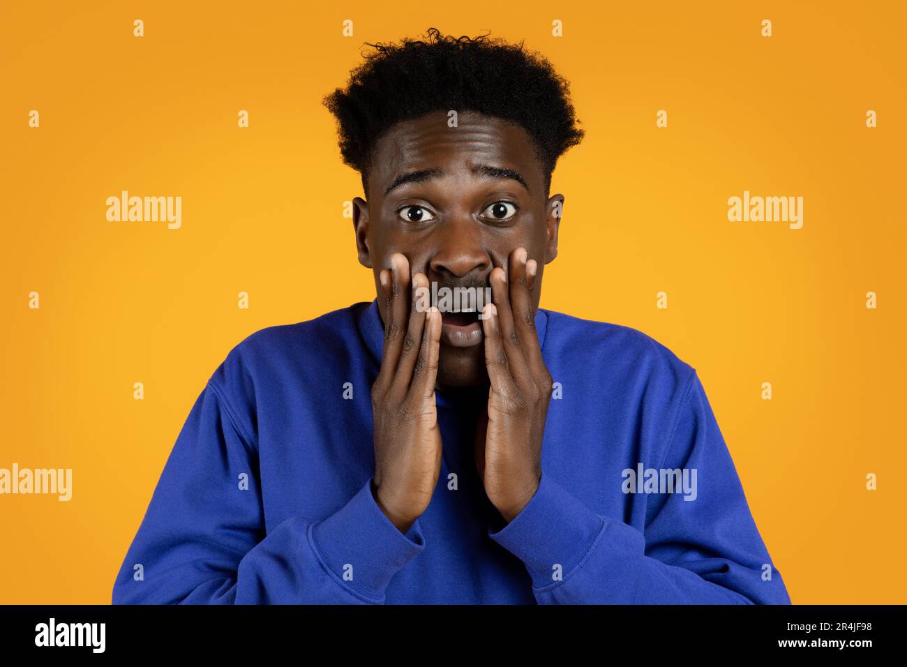 Shocked black man looking at camera, yellow background Stock Photo